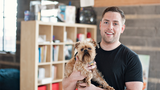 Young man carrying a small dog